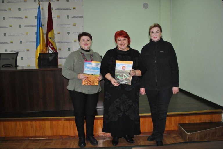 Три жінки стоять на сцені та тримають у руках книжки.