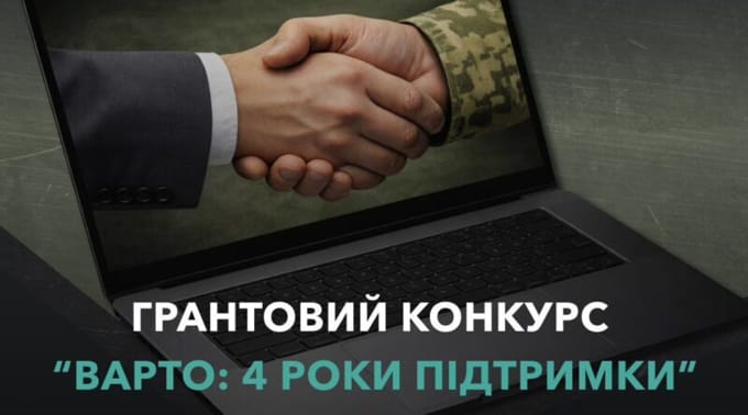 Два чоловікові руки міцно тиснуть одна одну на тлі екрана ноутбука, ліва рука в діловому костюмі, права в камуфляжній формі, під текстом про грантовий конкурс 