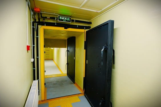 Велика чорна зачиненa двері з ручкою відкрита, поряд знаходиться відчиненa жовра рама дверей з написом 