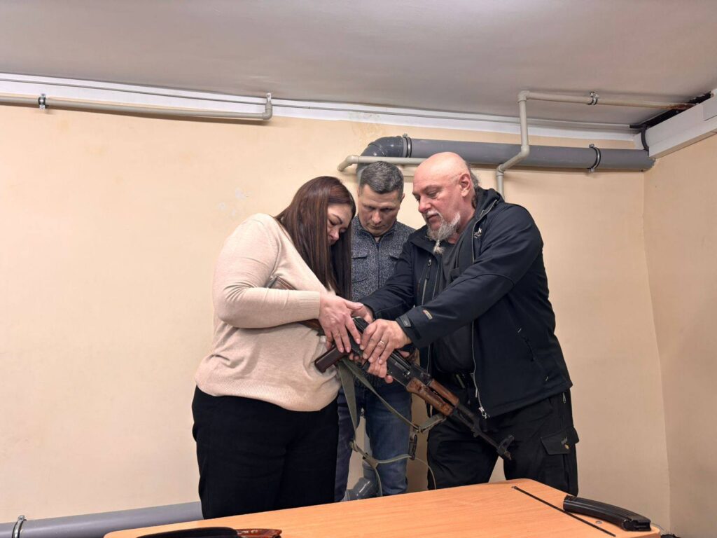 Жінка та двоє чоловіків розглядають автомат.