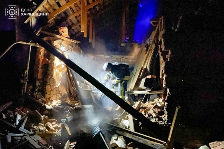 Рятувальник у темному приміщенні з уламками та димом обстежує місце події.