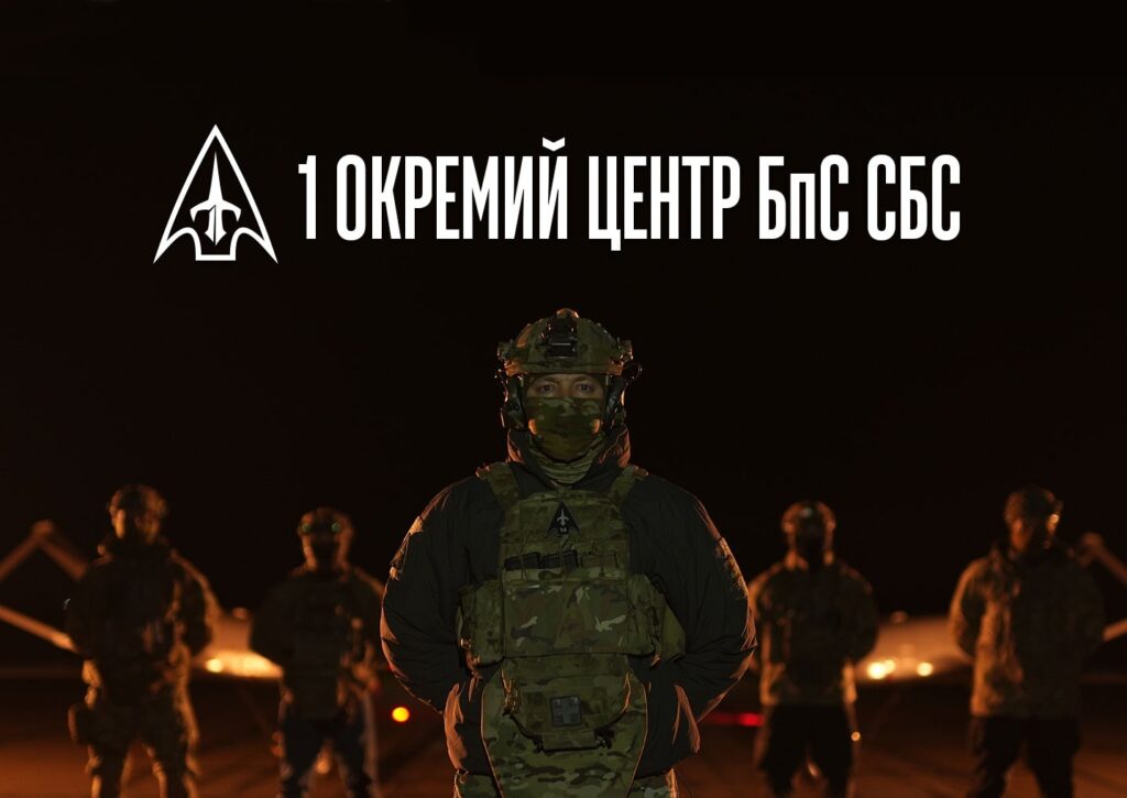 Військовослужбовець у камуфляжній формі та екіпіровці стоїть на передньому плані, за ним група військових.