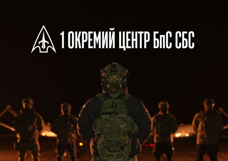 Військовослужбовець у камуфляжній формі та екіпіровці стоїть на передньому плані, за ним група військових.