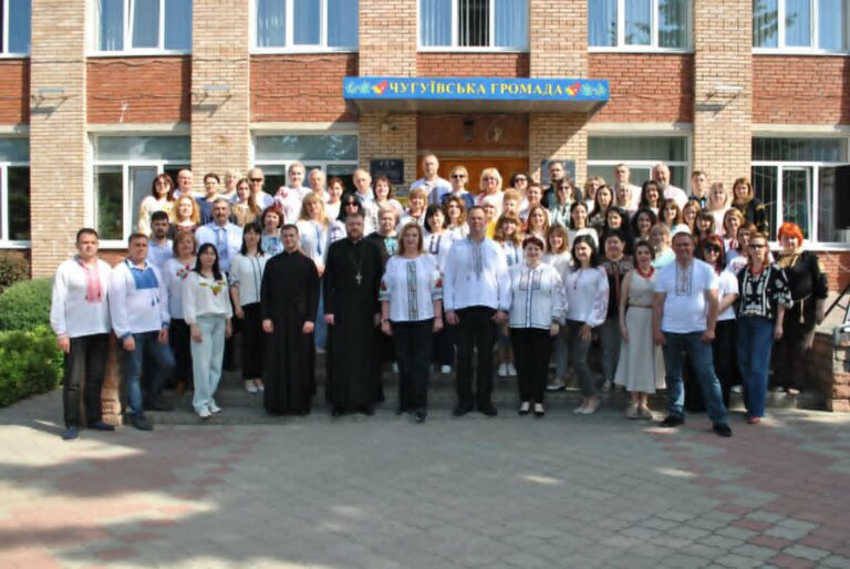 Велика група людей, переважно у вишиванках, зібралась перед будівлею з написом "Чугуївська громада".