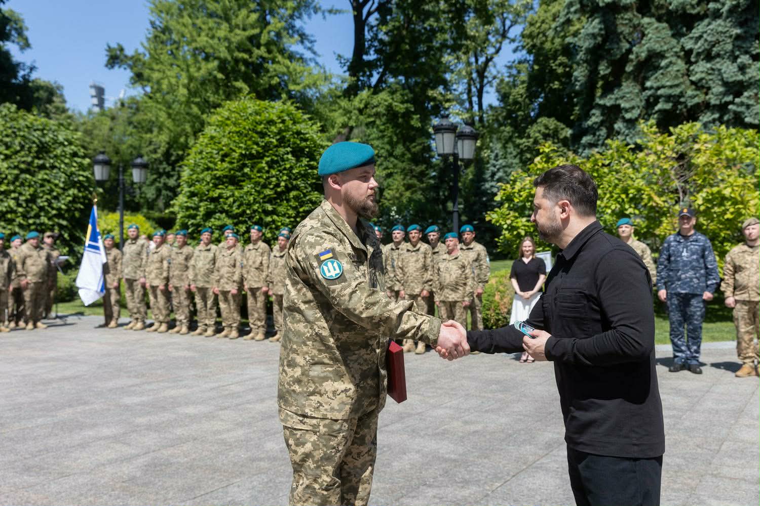 Президент України міцно тисне руку військовослужбовцю ЗСУ у камуфляжній формі та блакитному беретi.