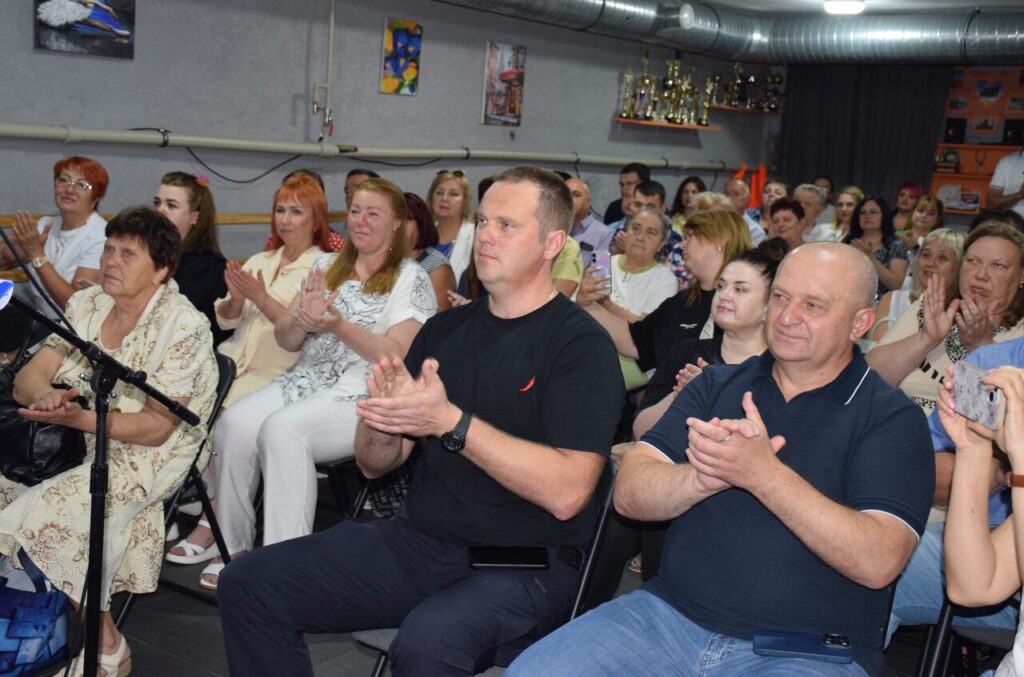 Група людей сидить на стільцях і плескає в долоні.
