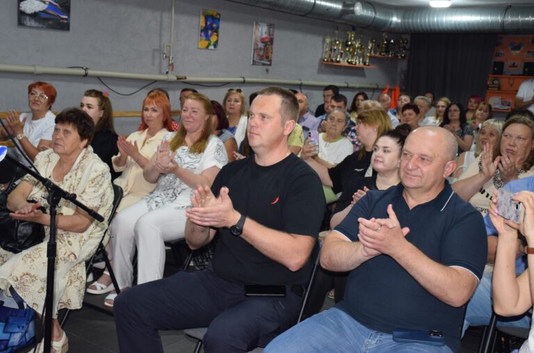 Група людей сидить на стільцях і плескає в долоні.