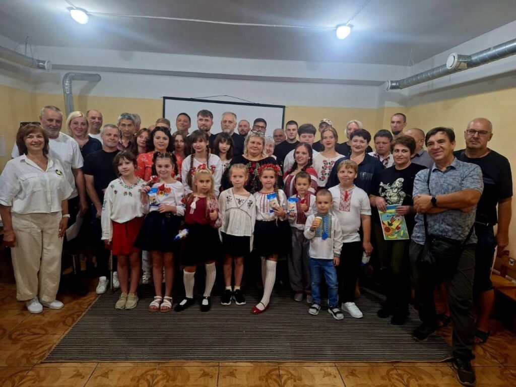 Група дорослих та дітей у традиційному українському одязі позує для колективного фото.