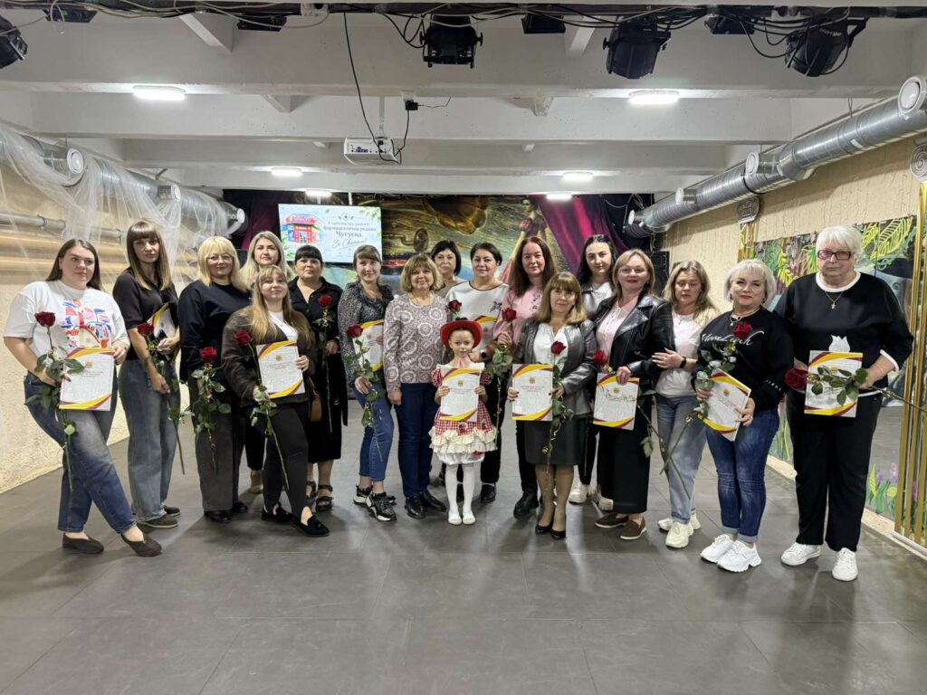 Група людей тримає в руках червоні троянди та сертифікати під час урочистої події.