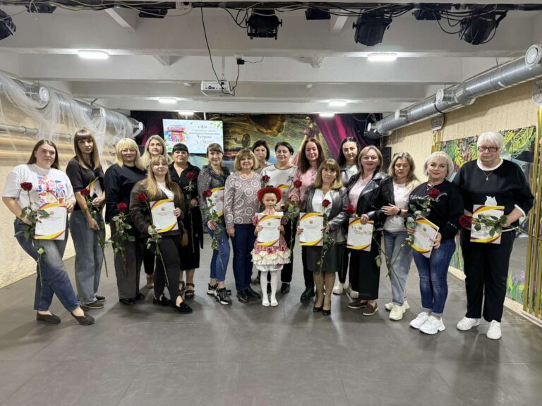 Група людей тримає в руках червоні троянди та сертифікати під час урочистої події.