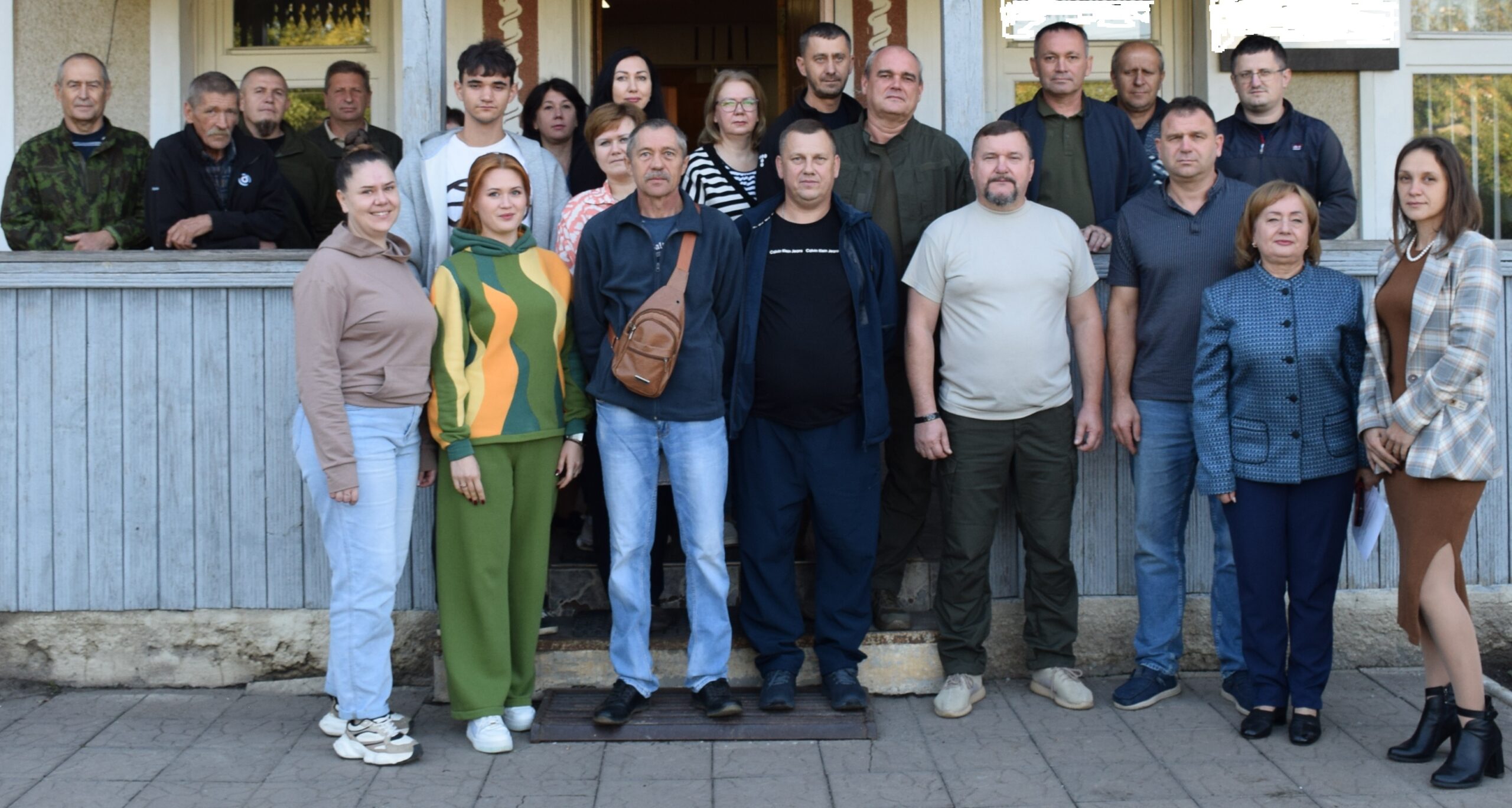 Група людей різного віку стоїть на сходах перед будівлею, утворюючи спільну групу.