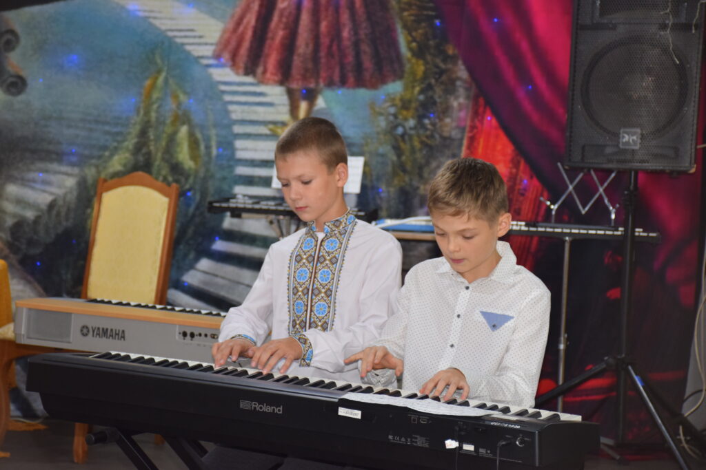 Два хлопці грають на електронних піаніно Roland та Yamaha на сцені.