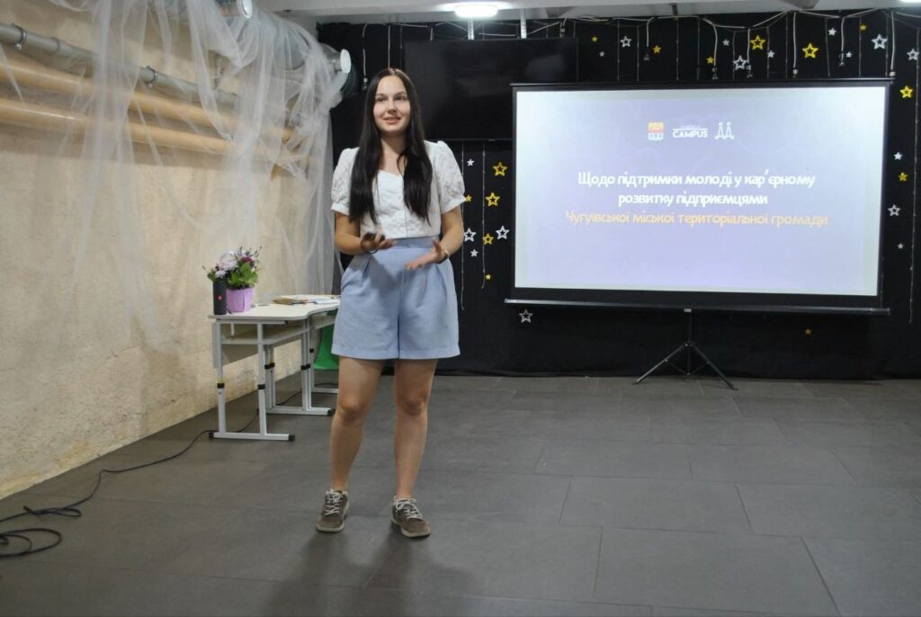Дівчина виступає біля екрана з презентацією про підтримку молоді у кар'єрному розвитку підприємцями.