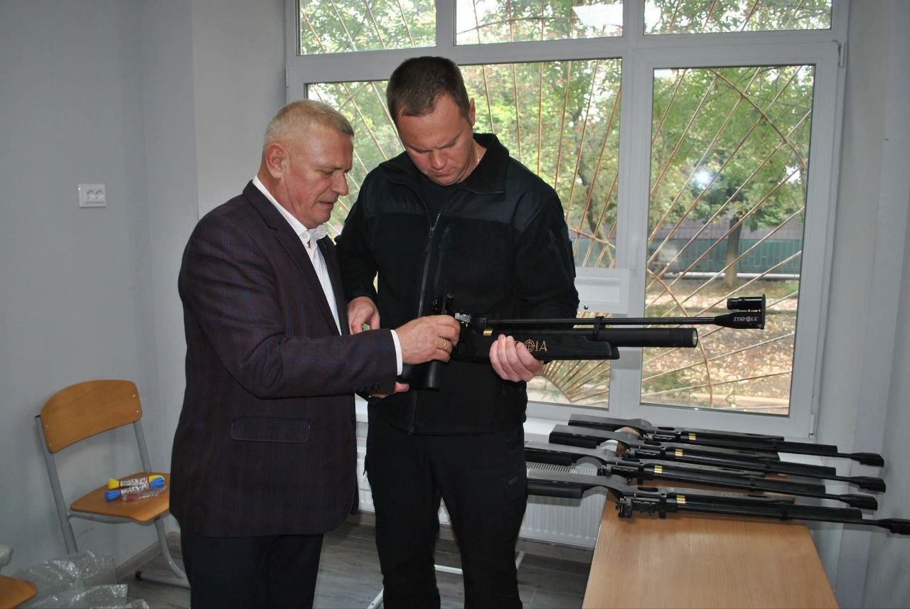Два чоловіки оглядають карабіни з написом 