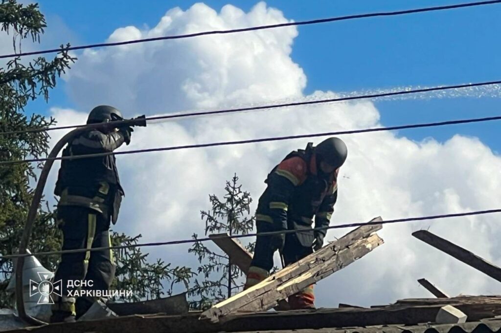 Рятувальники ДСНС Харківщини працюють на пошкодженій даху, де один спускає воду, а інший прибирає уламки.