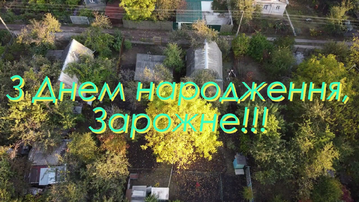 Повітряний знімок садиби з будинками та деревами, на якому великим кольоровим шрифтом написано привітання «З Днем народження, Зарожне!!!».