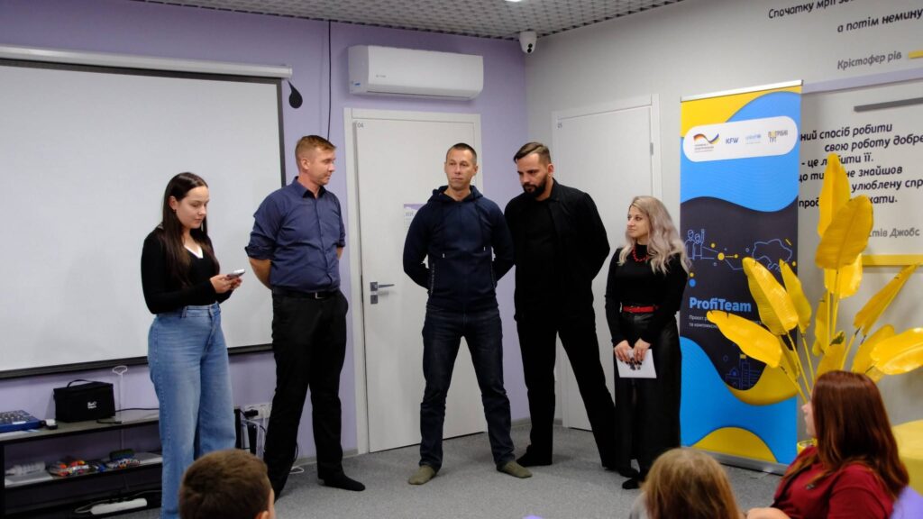 Група людей стоїть біля банера з написом 